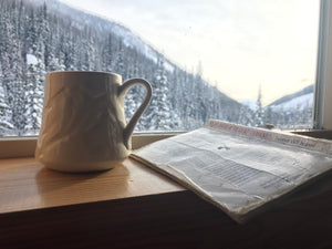 Coffee in a handmade mountain mug in a cabin on a wooden table beside a skier magazine